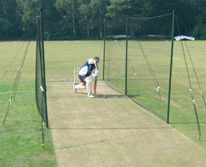 Cricket net supported by wooden poles and guy ropes.